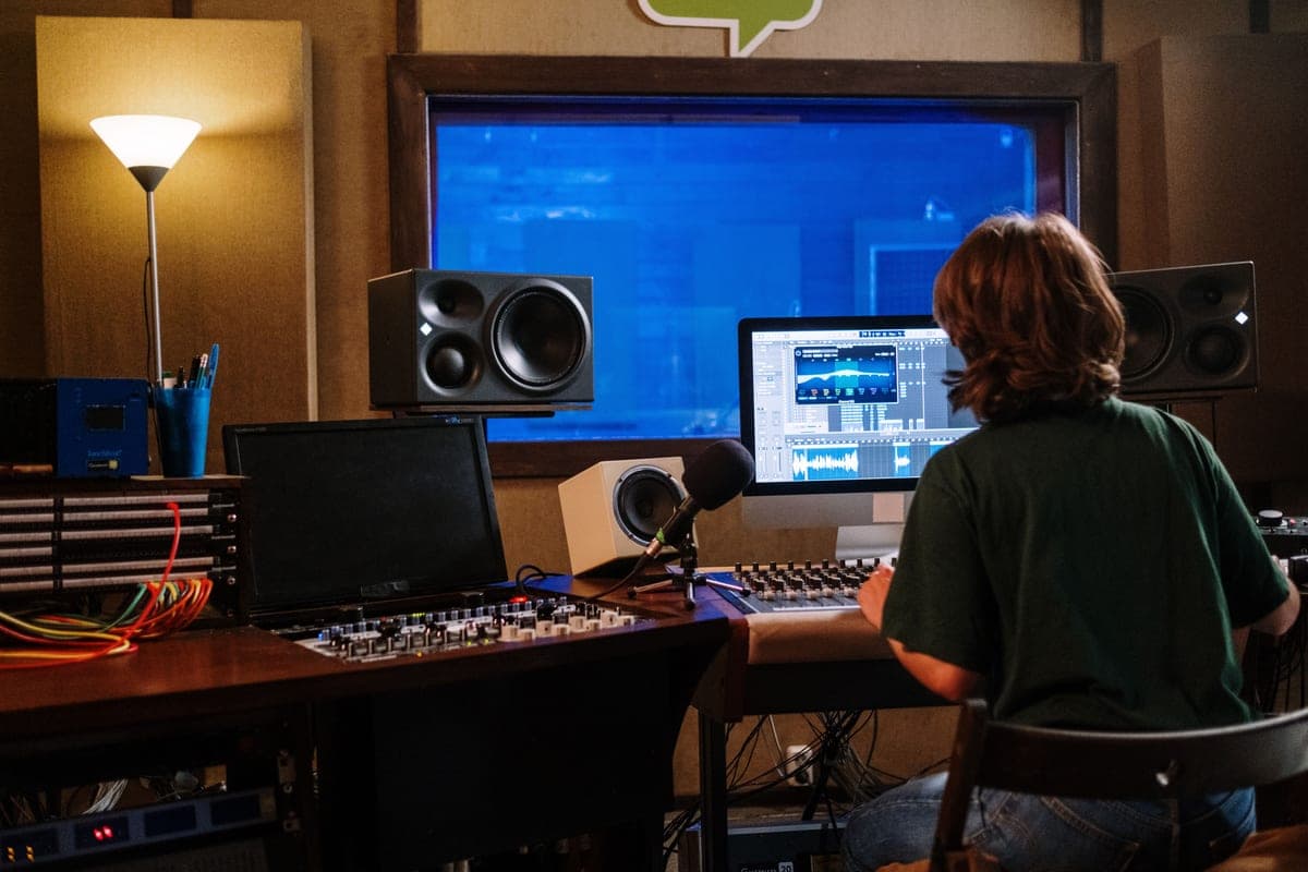 A studio monitor raised on a stand beside a desk